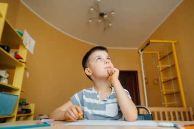 Okul çağındaki bir çocuk evde ödev yapar. Okulda eğitim.