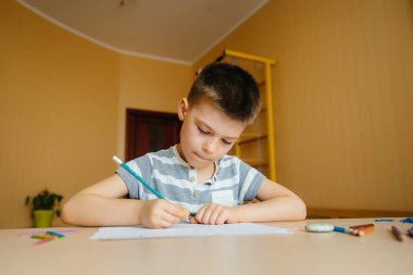 Okul çağındaki bir çocuk evde ödev yapar. Okulda eğitim.