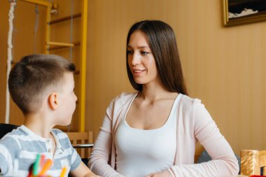 Genç bir anne evde oğluyla ev ödevi yapıyor. Ebeveynler ve eğitim