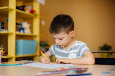 Okul çağındaki bir çocuk evde ödev yapar. Okulda eğitim.