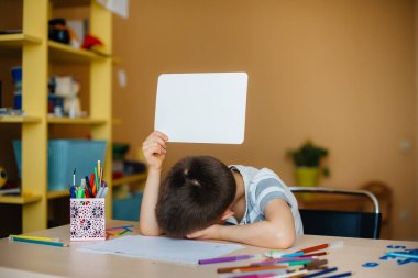 Okul çağındaki bir çocuk evde ödev yapar. Okulda eğitim.