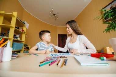 Genç bir anne evde oğluyla ev ödevi yapıyor. Ebeveynler ve eğitim