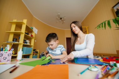 Genç bir anne evde oğluyla ev ödevi yapıyor. Ebeveynler ve eğitim