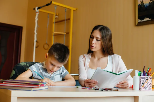 Genç bir anne evde oğluyla ev ödevi yapıyor. Ebeveynler ve eğitim