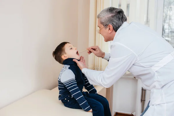 若い男の子が現代の診療所で経験豊富な医師の話を聞いて治療される ウイルスと伝染病 — ストック写真