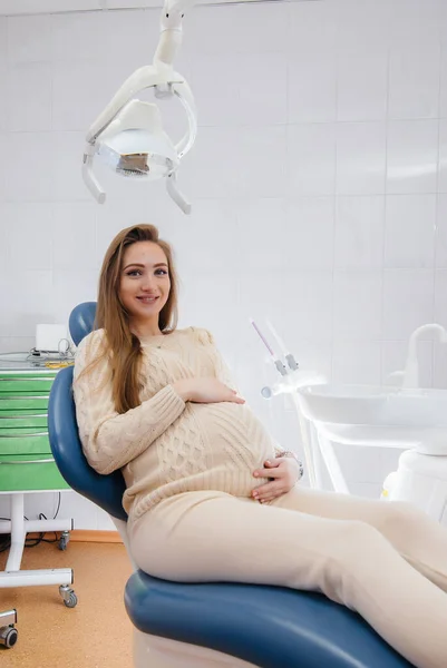 Profesyonel bir dişçi modern bir diş muayenehanesinde hamile bir kızın ağız boşluğunu tedavi eder ve muayene eder. Dişçilik