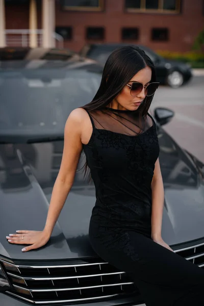 Κομψή Νεαρή Κοπέλα Στέκεται Κοντά Στο Αυτοκίνητο Ένα Μαύρο Φόρεμα — Φωτογραφία Αρχείου