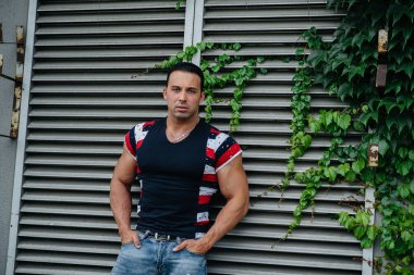 Sportif bir adam gri bir duvarın yanında duruyor. Yaşam biçimi