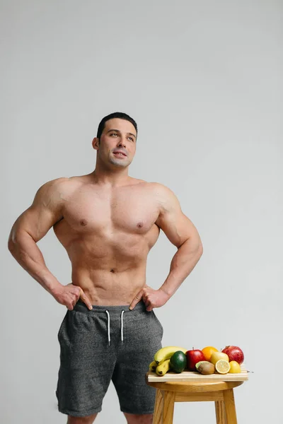 果物の隣にスタジオに裸の胴を持つセクシーなビーガン男 食事よ 健康的な食事 — ストック写真
