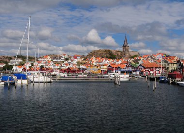 Güneşli bir yaz gününde limandan Fjallbacka şehrine gökyüzünde bulutlar olan bir manzara