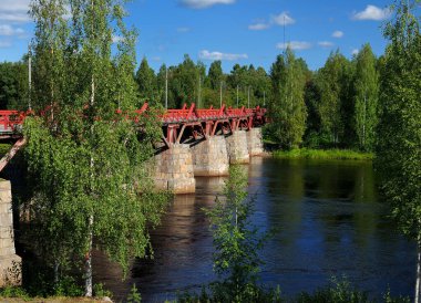 Güneşli bir yaz gününde açık mavi gökyüzüyle Skelleftea 'da Kırmızı Tahta Köprü Lejonstromsbron