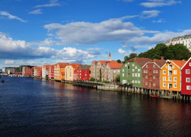 Gamle Bybru Köprüsü 'nden Bakklandet' in Trondheim 'daki renkli ahşap rıhtımına güneşli bir yaz günü açık mavi bir gökyüzü ve birkaç bulutla