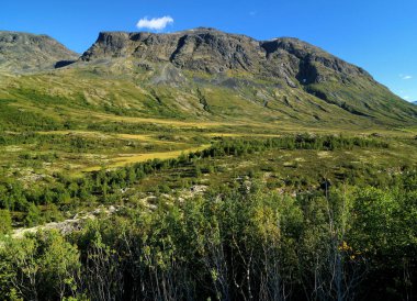 Güneşli bir yaz gününde Jotunheimen Ulusal Parkı 'nın çorak arazisindeki dağlar açık mavi bir gökyüzü ve birkaç bulutla