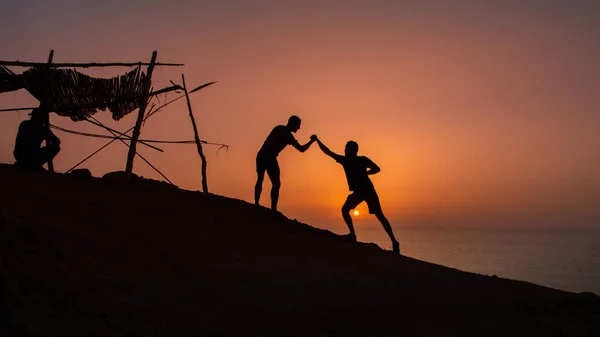 Silhouettes of friends jumping on a beach at sunset