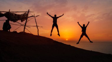  Gün batımında sahilde zıplayan arkadaşların siluetleri 