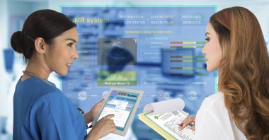 İki kadın doktorlar tarafından bir çalışma ile elektronik tıbbi kayıtları dijital tablet ve başka bir çalışma kağıt belgeler üzerinde birlikte çalışmak.