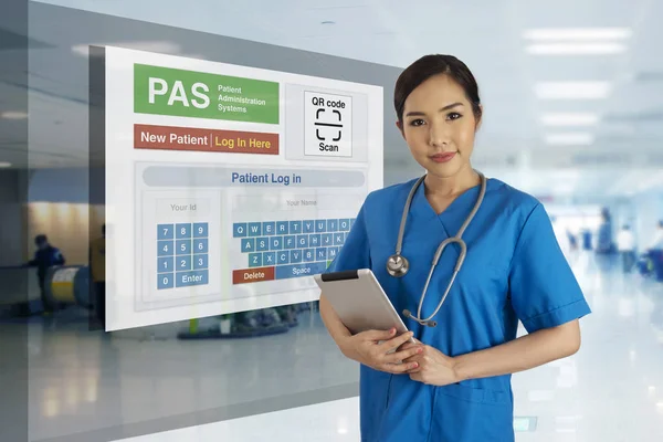 Female doctor in blue uniform standing in front of patient administration system screen that showing self registration for patient in hospital.