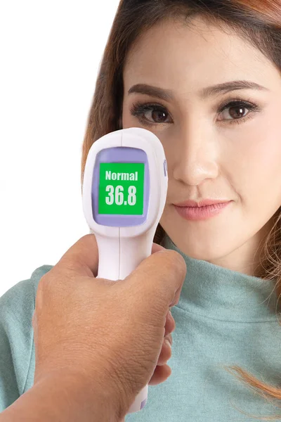 手はCovid 19の予防のために体温を測定する女性の顔を持つデジタル赤外線温度計を保持 — ストック写真