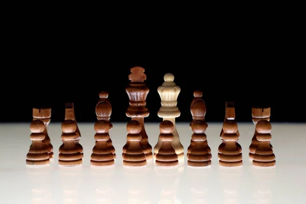 Black chess formation with a single white piece as a concept for undercover operations, infiltration, racial tension, ethnic minorities.
