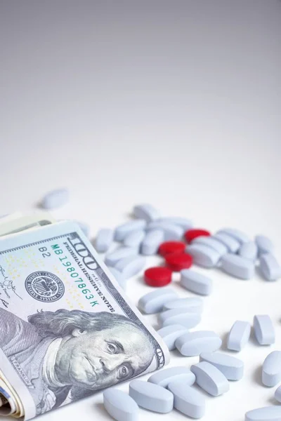 Health insurance, business concept. Red and blue pills on white background next to a wad of cash.