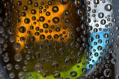 Koyu yağmur damlaları çok renkli arka plana doğru düşüyor. Yakın plan..