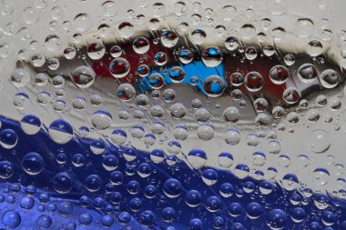 Yarı saydam mavi ve beyaz su damlaları bulutlu mavi gökyüzünün arka planına düşer. Soyut fantezi.