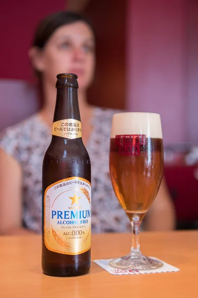 Sapporo Premium alkohol gratis öl i glas med suddig vackra kaukasiska kvinnor i bakgrunden — Stockfoto