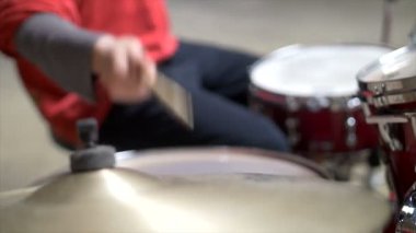 Bulanık, davul çalan adamın yakın çekimi, kırmızı davul seti ve kırmızı kıyafet.