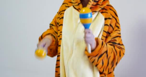 Oigenkännlig kvinnlig lärare spelar maracas bär söt tiger kigurumi kläder. Maracas är ett slagverk som ofta används för musikundervisning. — Stockvideo