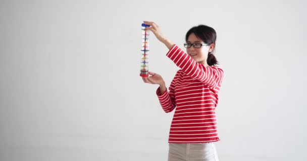 Bonito bela mulher brincando com rainstick, tubo cheio de pequenos seixos. Quando a vara é levantada, este instrumento de música está fazendo um som que lembra a queda de chuva. tiro UHD profissional . — Vídeo de Stock