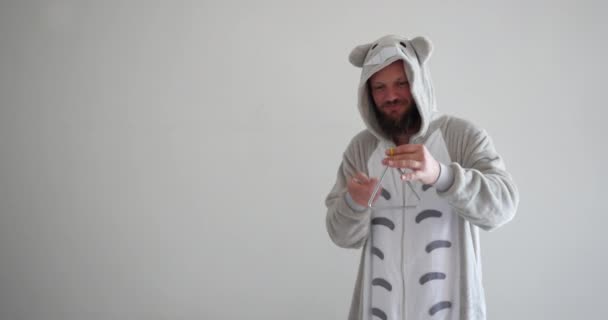 Loco guapo atractivo barbudo hipster con totoro pijama tocando el triángulo, un instrumento de música de percusión utilizado en la educación artística para la juventud . — Vídeos de Stock