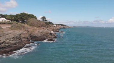 Kayalık kayalıklardaki geleneksel Fransız balıkçı kulübesinin güzel drone görüntüsü, küçük bulutlu mavi gökyüzü ve yeşil deniz suyu portföyü, Fransa 1-9-19