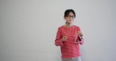 cute smiling Petite woman wearing fashion red striped clothes smiling and playing the triangle. natural makeup and normal behaviour. professional 4K shot of Chinese actress.