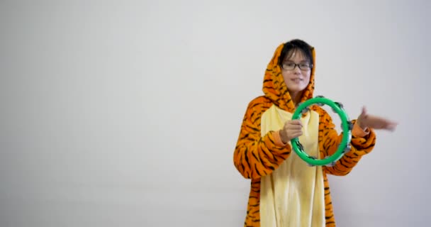 Chinese woman playing music instrument: the tambourine. Also wearing tiger synthetic animal fur clothes. Happy and funny feeling for this professional shot with asian beautiful cute women — 비디오