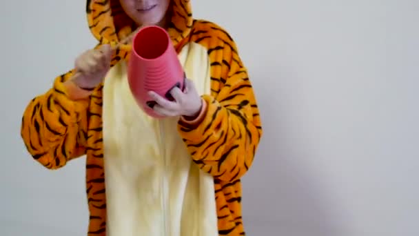 Guru wanita yang tidak dikenal bermain guiro mengenakan pakaian harimau kigurumi yang lucu. Guiro adalah instrumen dari america selatan yang sering digunakan dalam musik salsa — Stok Video