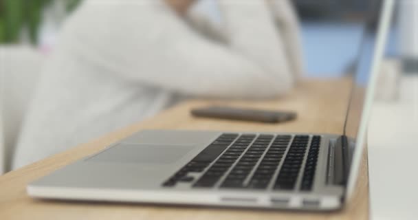 4K Primer plano de las manos de un hombre que trabaja en un ordenador portátil durante la reunión de negocios. otros trabajadores silueta borrosa en brillante Lit fondo de la oficina. Touchpad táctil con los dedos Teléfono inteligente que se encuentra cerca . — Vídeos de Stock