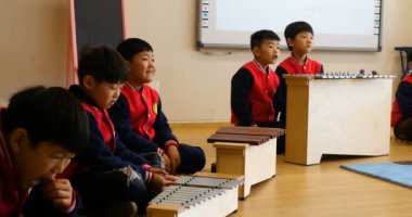 Bir grup Asyalı çocuk müzik eğitimi dersinde perküsyon çalıyorlar. Çinli öğrenciler müziği sever, eğlenceli olduğu için mutludurlar! Şangay Çin, 9 / 12 / 18