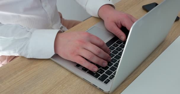 Красивый привлекательный бизнесмен, печатающий на клавиатуре компьютера в белой рубашке, современный стартап уверенный в себе бизнесмен руки на клавиатуре со смартфоном, лежащим рядом. 4K UHD-съемка — стоковое видео