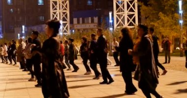 Çinli orta yaşlı ve yaşlı insanlar dans edip egzersiz yapıyor. Sağlıklı yaşam tarzı, şehir meydanında geleneksel dans, Çince işaretler: süpermarket, erişte, Bbq, Dalian, Çin Aralık 2018