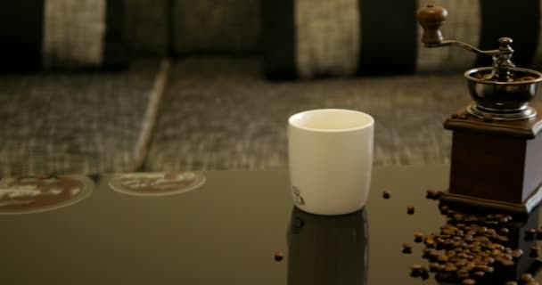 ブラックデザインのアラビカ豆と白マグカップ付きの古いスタイルのコーヒーグラインダー背景にぼやけたグレーのソファと光沢のあるテーブル 水平方向の旅行 — ストック動画