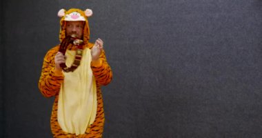 Öğretmen Kigurumi kaplan pijaması giymiş, tef çalıyor.