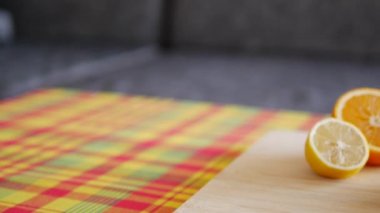 Renkli taze meyveler içeren portakal suyu çeşnili güzel, yatay meyve tabağı. Tahta tabakta portakal ve limon ve Karayip madras masa örtüsü.