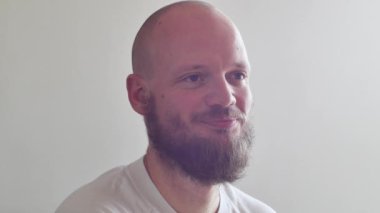 Yakışıklı Sakallı Adam gülümsüyor. Profesyonel hippi ve şık modelin çok havalı bir gülümsemesi. Profil, beyaz gömlek, 35 yaşında.