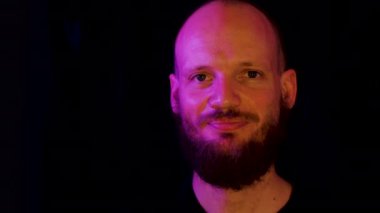 Tuhaf pembe ve sarı ışık, adam nazikçe bakıyor sonra gülümsüyor, garip bir bakış ve tuhaf bir ortam..