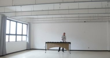 Boş bir odada camlı beyaz elbiseler içinde marimba çalan bir adam. Bu izole edilmiş profesyonel müzisyen için 3D tavan arası tasarımı atmosferi. Temiz kavram.