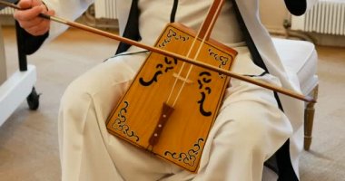 Müzisyen vücudunun Morin Khuur, Moğolca iki telli fiyonklu tahta çelloyu çaldığı yakın plan. Beyaz elbiseler giyiyordu. Güzel müzik ve tanınmayan bir müzisyen.