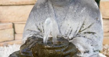 Tropikal bahçede şelaleli taş Buda heykeli, bahçe çiçeklerinde küçük Buda heykeli. Çiçek bahçesindeki gri Buda heykelinin yakınına lupinler ve bambularla.