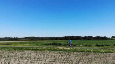 Altın gün batımı, yokuş yukarı pedal çeviren genç bir dağ bisikletçisinin yolunu aydınlatıyor. Atletik bir erkek turist boyunca uçuyor elektrikli bisikletiyle sabahın erken saatlerinde dik çimenli bir tepede..