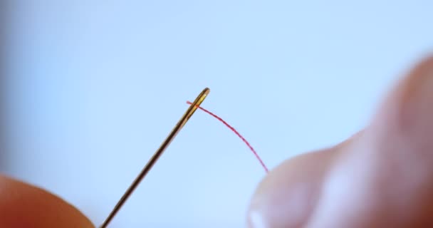 Cinematic shot of red thread passing through sewing needle. man sewing project by hand. handmade suit garment with quality thread and fabric. DIY beautiful quilting by fashion creative seamstress — Stock Video