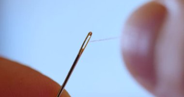 Moda terzisinin eli dikiş iğnesinden geçen beyaz iplik. Adam projeyi elleriyle dikiyor. Kaliteli iplik ve kumaştan yapılmış el yapımı elbise. DIY ve güzel yorganlar